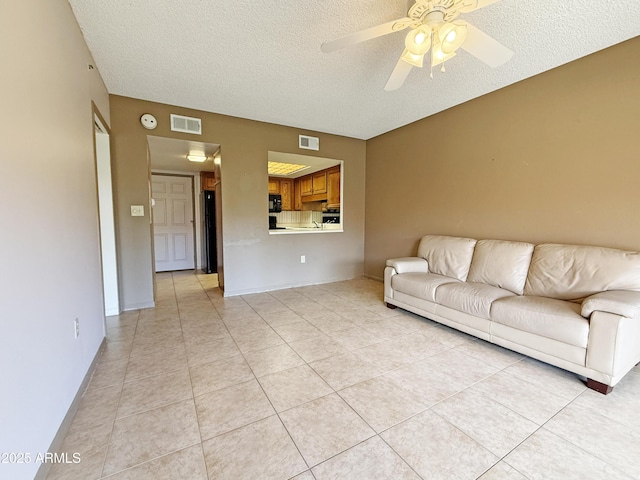 unfurnished living room with ceiling fan, a textured ceiling, and light tile patterned floors