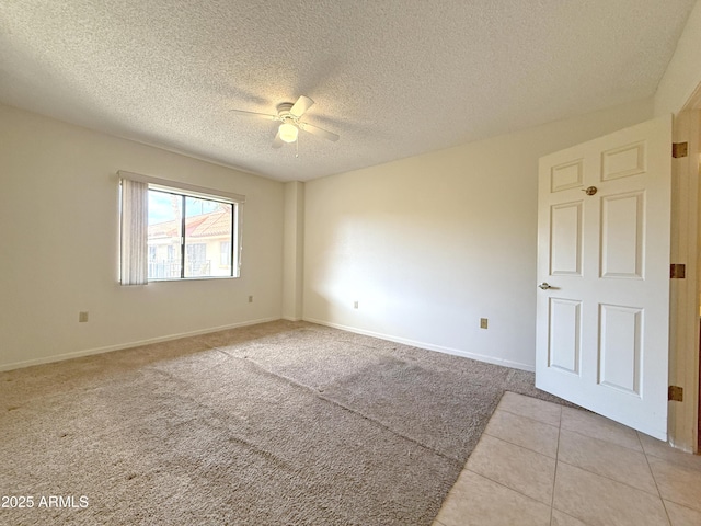 empty room featuring ceiling fan, light colored carpet, and a textured ceiling