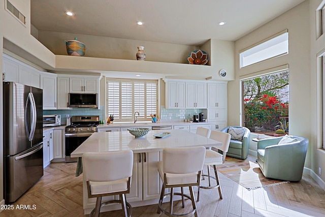 kitchen with visible vents, light countertops, white cabinets, tasteful backsplash, and appliances with stainless steel finishes