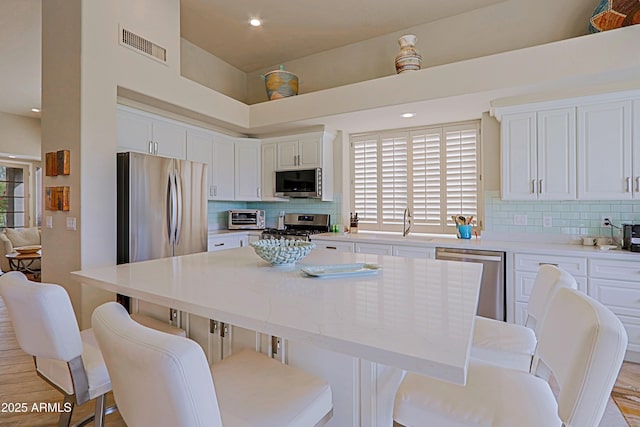 kitchen with visible vents, tasteful backsplash, a center island, and stainless steel appliances