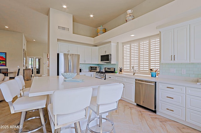 kitchen with a sink, appliances with stainless steel finishes, a breakfast bar, and white cabinetry