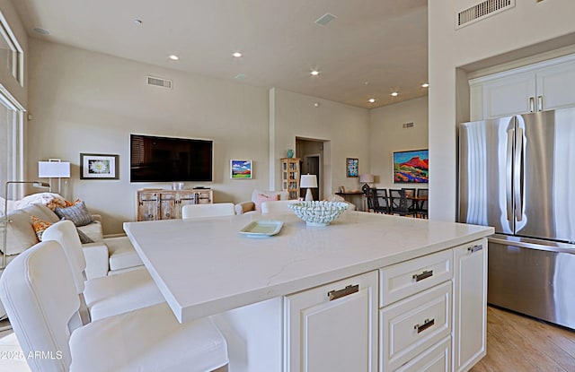 kitchen featuring visible vents, freestanding refrigerator, open floor plan, and light stone countertops