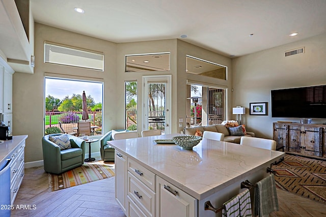 kitchen featuring white cabinets, recessed lighting, open floor plan, and visible vents