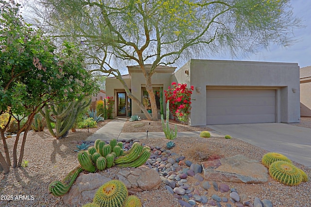 pueblo revival-style home with an attached garage, stucco siding, and concrete driveway