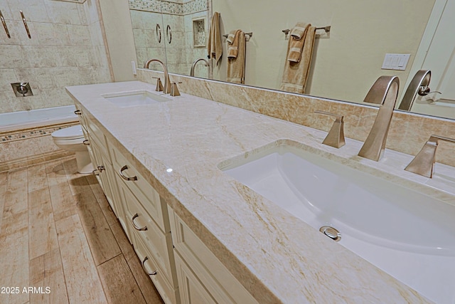 bathroom featuring double vanity, a sink, tiled shower / bath combo, and toilet