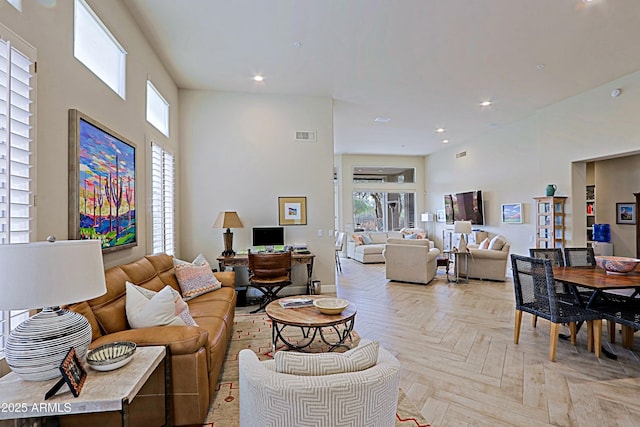 living room featuring recessed lighting, baseboards, plenty of natural light, and a towering ceiling