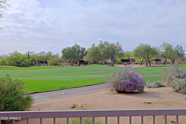 view of community featuring view of golf course and a yard