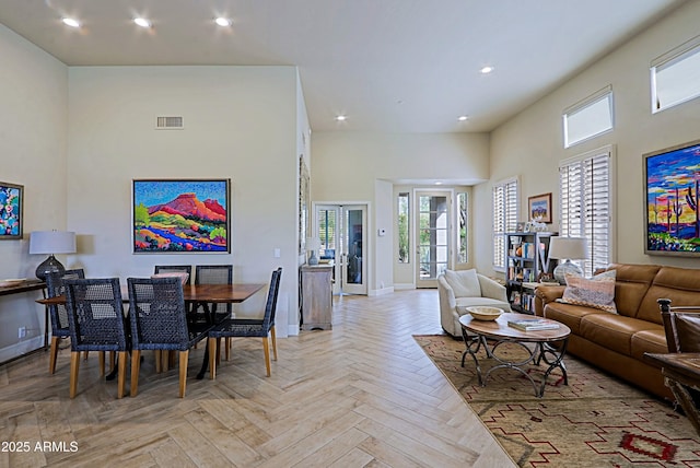 living room featuring visible vents, recessed lighting, plenty of natural light, and a towering ceiling