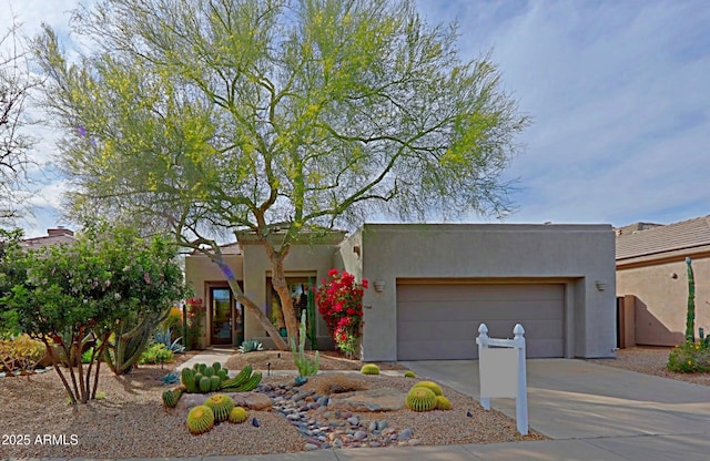 adobe home featuring concrete driveway, an attached garage, and stucco siding