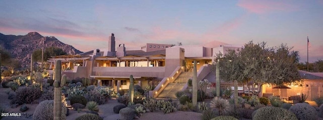 back of house at dusk with stairs, stucco siding, and a mountain view