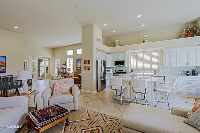 living area featuring plenty of natural light, a high ceiling, recessed lighting, and visible vents