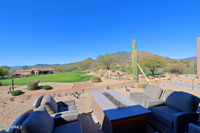 view of patio featuring a mountain view, golf course view, and an outdoor living space with a fire pit