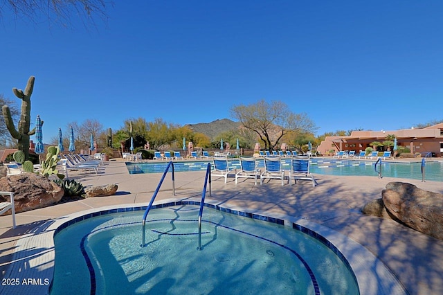 pool with a mountain view, a community hot tub, and a patio area