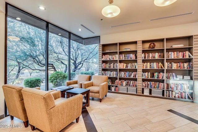 sitting room with tile patterned floors, plenty of natural light, expansive windows, and visible vents