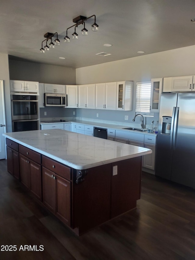 kitchen with glass insert cabinets, white cabinetry, a sink, and black appliances