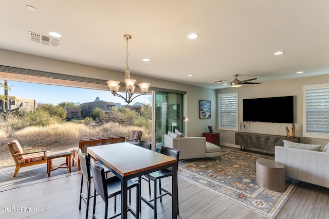 dining space featuring ceiling fan with notable chandelier