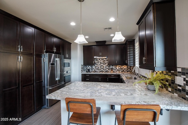 kitchen with pendant lighting, appliances with stainless steel finishes, sink, and a breakfast bar area