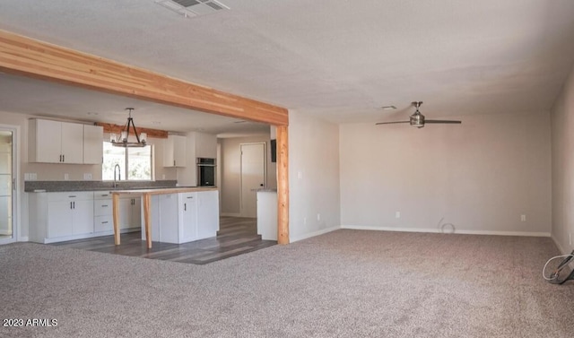 kitchen with sink, white cabinets, a center island, dark carpet, and stainless steel oven