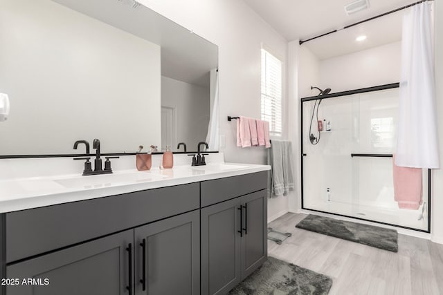 bathroom with vanity, a shower with shower door, and hardwood / wood-style floors