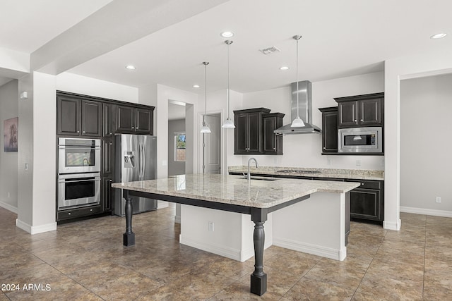 kitchen featuring appliances with stainless steel finishes, sink, an island with sink, wall chimney exhaust hood, and a breakfast bar area