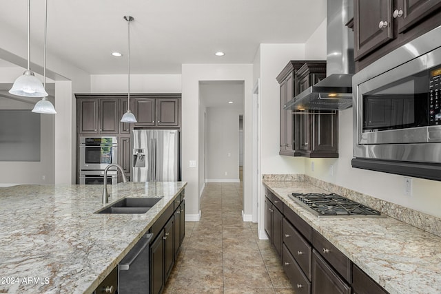 kitchen with dark brown cabinets, light stone countertops, stainless steel appliances, sink, and decorative light fixtures