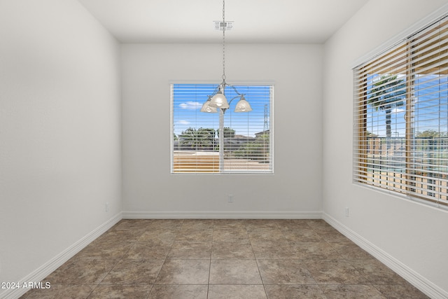 unfurnished dining area featuring tile patterned floors, a notable chandelier, and plenty of natural light