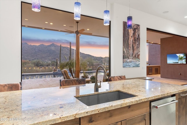 kitchen with dishwasher, light stone countertops, sink, and decorative light fixtures