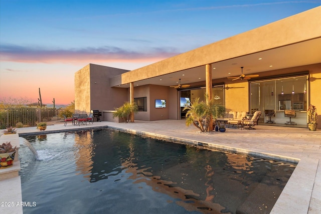 pool at dusk with a patio area and ceiling fan