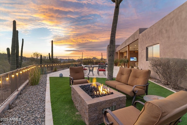 patio terrace at dusk featuring an outdoor living space with a fire pit