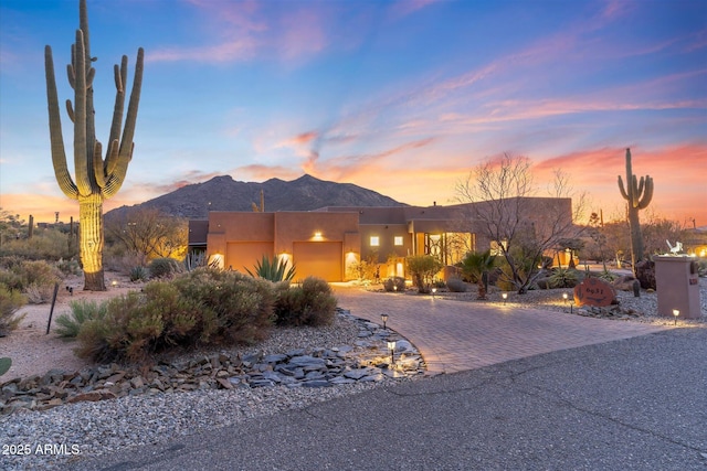 pueblo-style house with a garage and a mountain view