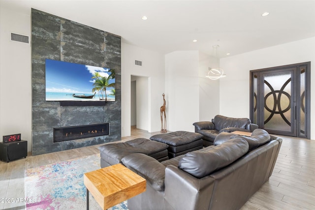 living room with a tile fireplace and light hardwood / wood-style flooring