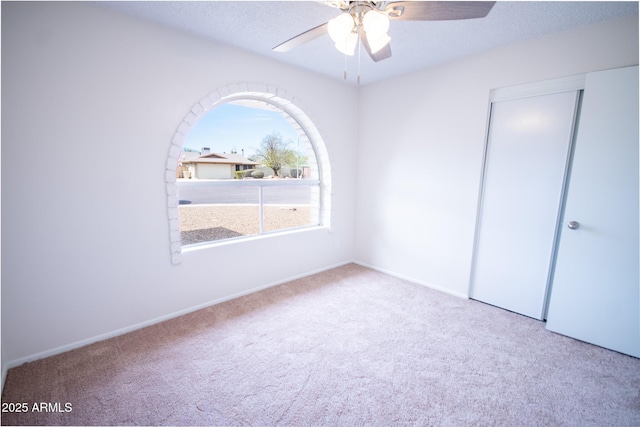 carpeted spare room featuring ceiling fan