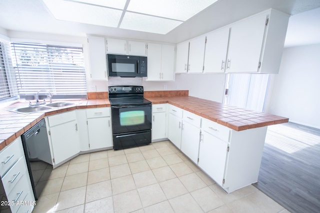 kitchen with tile counters, white cabinets, and black appliances