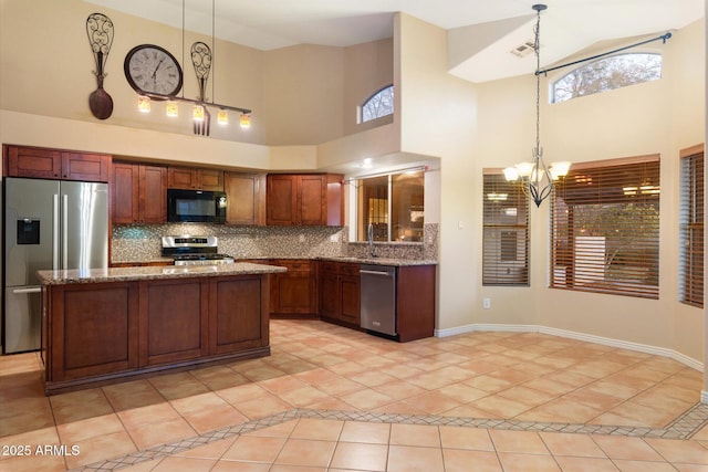 kitchen with hanging light fixtures, light tile patterned floors, a notable chandelier, light stone counters, and stainless steel appliances