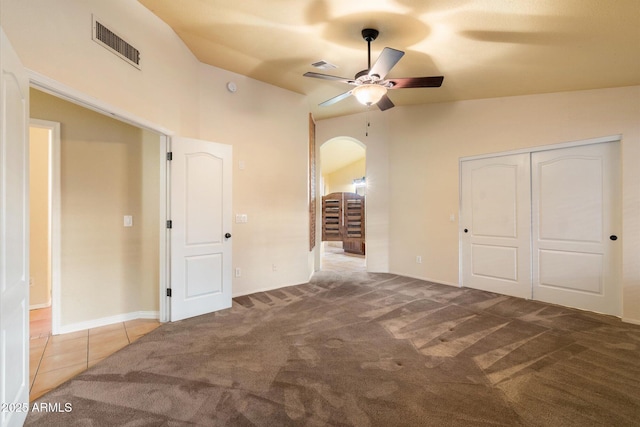 unfurnished bedroom featuring vaulted ceiling, light colored carpet, ceiling fan, and a closet