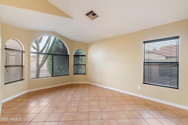 tiled empty room featuring lofted ceiling