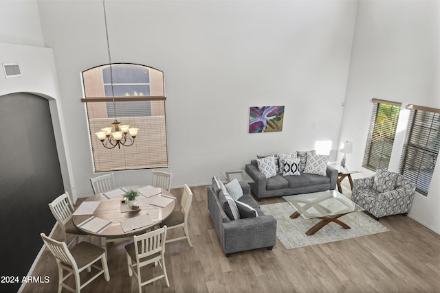 living room with hardwood / wood-style flooring, a high ceiling, and an inviting chandelier