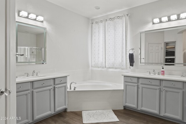 bathroom with vanity, wood-type flooring, and plus walk in shower