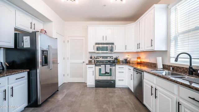 kitchen with dark stone counters, sink, stainless steel appliances, and white cabinetry