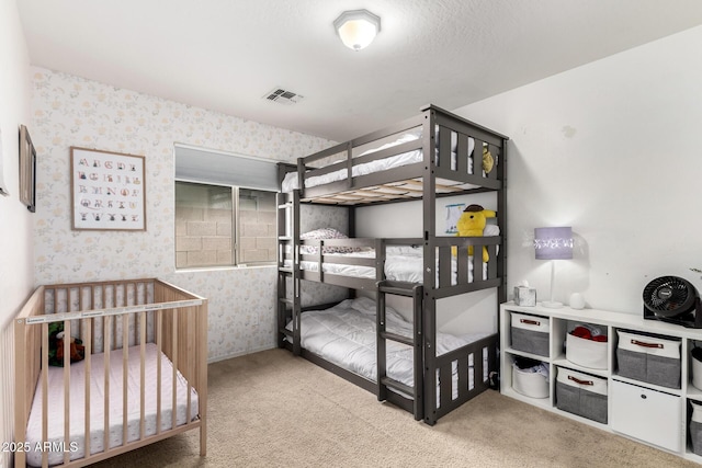 carpeted bedroom featuring visible vents and wallpapered walls