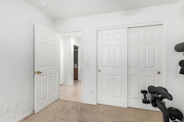 exercise area with light tile patterned floors, baseboards, and light carpet