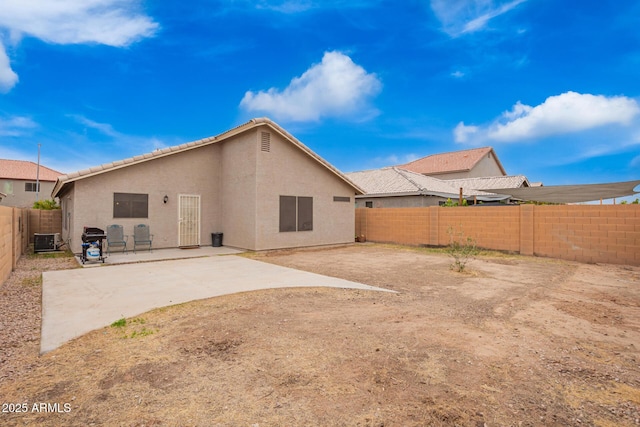 rear view of house with a fenced backyard, stucco siding, central AC, and a patio