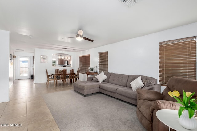 living area featuring light tile patterned floors, a ceiling fan, and visible vents