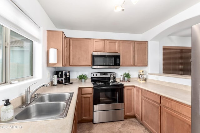 kitchen with a sink, appliances with stainless steel finishes, light tile patterned floors, and light countertops