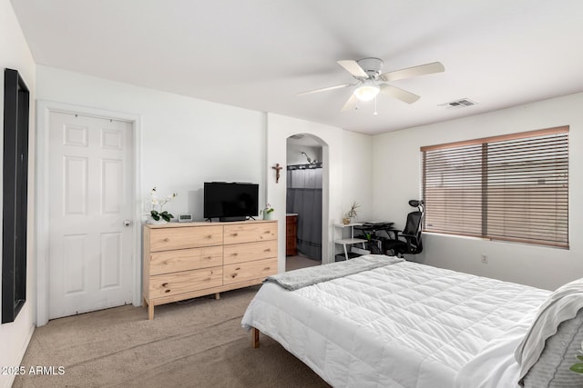 bedroom featuring arched walkways, visible vents, light colored carpet, and ceiling fan