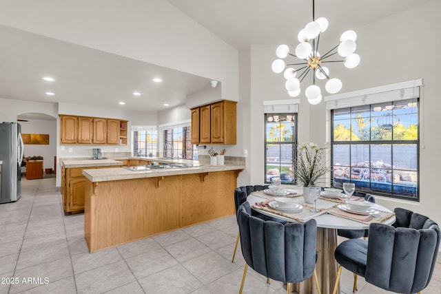 7763 W Libby St, Glendale, AZ 85308 - kitchen featuring a chandelier, a breakfast bar area, arched walkways, a peninsula, and freestanding refrigerator