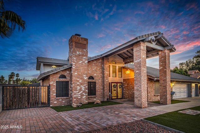 7763 W Libby St, Glendale, AZ 85308 - view of front of property with a gate, driveway, a chimney, brick siding, and a garage