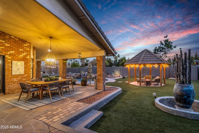7763 W Libby St, Glendale, AZ 85308 - patio terrace at dusk with a fenced backyard, a gazebo, a yard, and outdoor dining area