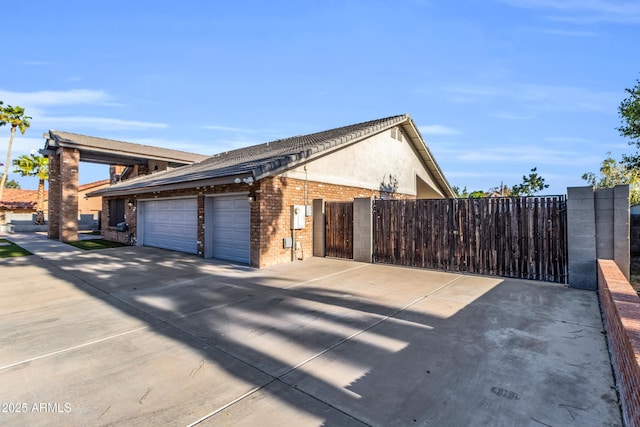 7763 W Libby St, Glendale, AZ 85308 - view of property exterior with driveway, fence, a garage, stucco siding, and brick siding