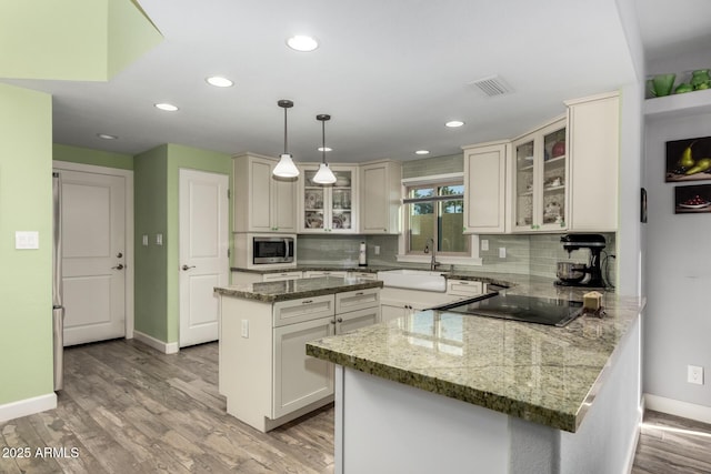 kitchen featuring sink, hanging light fixtures, a center island, black electric stovetop, and decorative backsplash